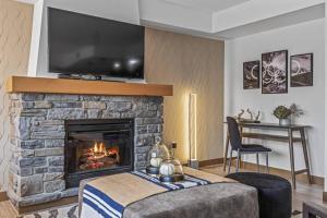 a living room with a fireplace with a tv above it at Free Arcade Delightful Stay in Rocky Mountains in Dead Man's Flats