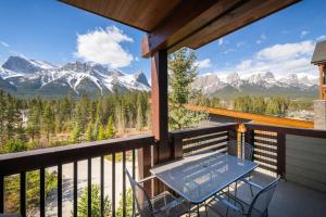 Serene 3BR Rockies Stay with Hot Tub and Near DT في كانمور: شرفة مع طاولة وكراسي وجبال