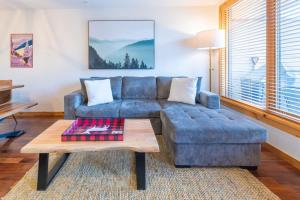 Serene 3BR Rockies Stay with Hot Tub and Near DT في كانمور: غرفة معيشة مع أريكة زرقاء وطاولة قهوة