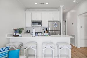 a kitchen with white cabinets and a counter with stools at Mississippi Gulf Coast Basecamp-Central Location in Pass Christian +16 photos