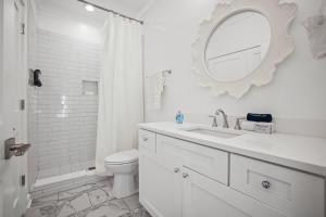 a white bathroom with a sink and a mirror at Mississippi Gulf Coast Basecamp-Central Location in Pass Christian