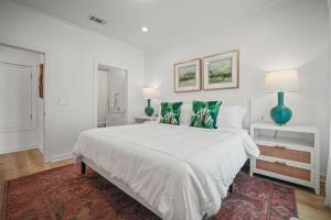 a white bedroom with a large bed with green pillows at Mississippi Gulf Coast Basecamp-Central Location in Pass Christian
