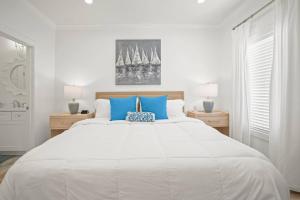 a white bedroom with a large white bed with blue pillows at Extended Stay Friendly-Full Kitchen & Laundry in Pass Christian