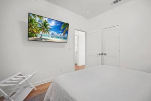 a white bedroom with a bed and a painting on the wall at Beach Access Condo-Walk to Downtown-Pets Welcome w/ Fee in Pass Christian