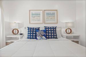 a white bed with blue and white pillows on it at Beach Access Condo-Walk to Downtown-Pets Welcome w/ Fee in Pass Christian