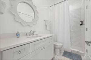 a white bathroom with a sink and a mirror at Beach Access Condo-Walk to Downtown-Pets Welcome w/ Fee in Pass Christian +18 photos