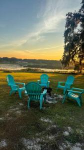 a group of three blue chairs sitting in the grass at Waterfront home with Firepit and Foosball Table in Fruitland Park