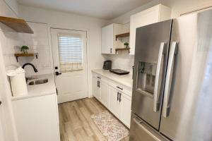 a kitchen with white cabinets and a stainless steel refrigerator at Waterfront home with Firepit and Foosball Table in Fruitland Park