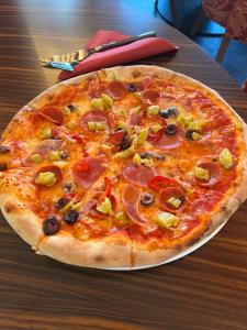 a pizza with pepperoni and olives on a table at CineHotel Maroni in Zirndorf