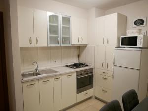 eine Küche mit weißen Schränken und einer Spüle und einer Mikrowelle in der Unterkunft Queen's gate in Zagreb + 9 Fotos