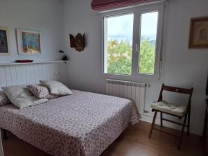 a bedroom with a bed and a chair and a window at La Pabla in Colunga
