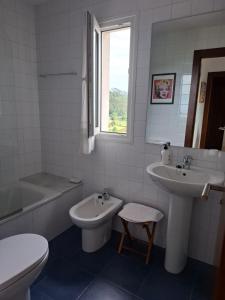 a white bathroom with a sink and a toilet and a tub at La Pabla in Colunga