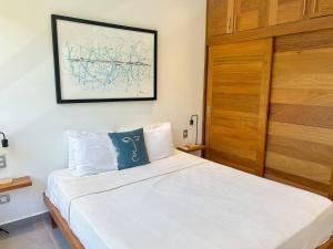 a bedroom with a white bed with a wooden door at Villa Hazel in Las Terrenas +14 photos