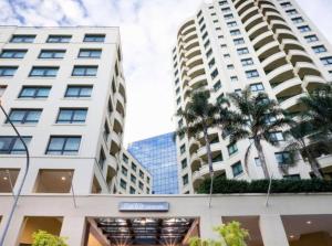 Opulent one bedroom apartment in parramatta. في سيدني: مبنيان طويلان في مدينة بها أشجار النخيل