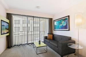 Opulent one bedroom apartment in parramatta. في سيدني: غرفة معيشة مع أريكة ونافذة كبيرة