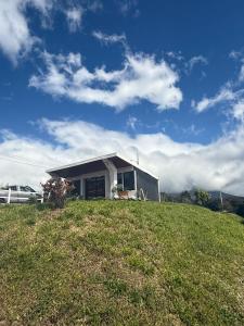 a small house on top of a grassy hill at Green haven Poas in Poasito