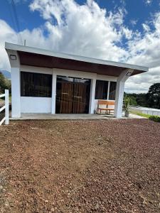 a small white house with a bench in front of it at Green haven Poas in Poasito