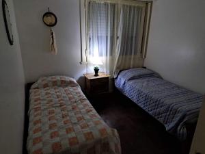 a bedroom with two beds and a window with a clock at Departamento 3 Ambientes Plaza Colon in Mar del Plata