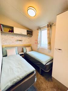 Una pequeña habitación con dos camas y una ventana. en Billing Aquadrome - Bird Lake View, en Great Billing