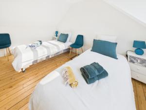 two white beds in a room with blue chairs at Loki Rivoli Cottage in Locquirec