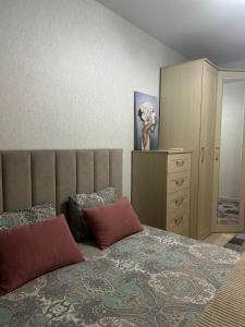 a bedroom with a large bed and a dresser at Уютная 2 ком.квартира in Kostanay