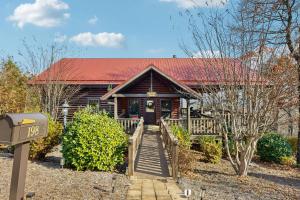 une cabane en rondins avec un toit rouge et une passerelle en bois dans l'établissement Boulder Ridge Cabin, à Lake Lure