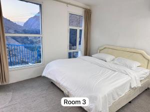 a white bedroom with a bed with a window at Hawer Inn - wadi bani Khalid in Biḑ‘ah