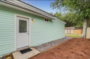 a green building with a white door and a yard at Northeast Investments LLC in Gulfport