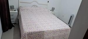 a bedroom with a bed with a flowered blanket on it at Casa Flor Apartment in Ribeira Grande