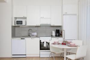 a white kitchen with a table and white cabinets at Arctic Aurora Suite Rovaniemi in Rovaniemi