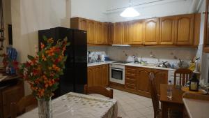 eine Küche mit Holzschränken und einem schwarzen Kühlschrank in der Unterkunft Elias House in Nafplio
