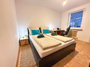SchalchhamApartment - Nähe Bahnhof - Arbeitsplatz - Badewanne - Piano的一间卧室配有一张大床、一张桌子和一个窗户。