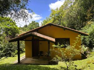 a small yellow house in the middle of a field at Pousada Roca in Ibiúna