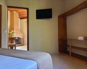a bedroom with a bed and a tv on the wall at Pousada ROCA in Ibiúna