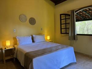 a bedroom with a bed with two lamps and a window at Pousada Roca in Ibiúna