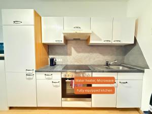 SchalchhamApartment - Nähe Bahnhof - Arbeitsplatz - Badewanne - Piano的带白色橱柜和水槽的厨房