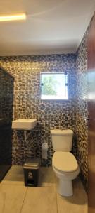 Un baño con inodoro, lavabo y ventana. en Pousada Ilha Sul, en Cananéia