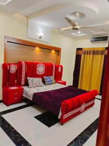 a bedroom with a red bed and a chair at Komal Residency in Islamabad