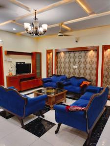 a living room with blue chairs and a tv at Komal Residency in Islamabad