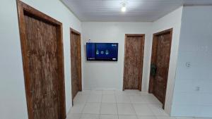 Una habitación con dos puertas y un televisor en la pared. en Refúgio do Pontal, en Palhoça