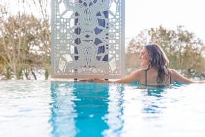 a woman is in a swimming pool at Best Western Plus Le Roi Arthur Hôtel & Spa in Ploërmel