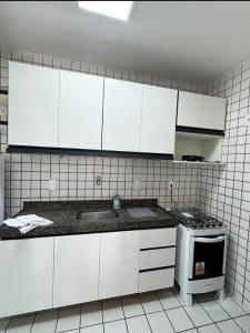 a kitchen with white cabinets and a sink and a stove at Edifício Atlantis Hotel in Maceió