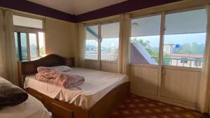 a bedroom with two beds and a large window at Hotel Sauraha Gaida House in Chitwan +193 photos