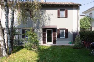 a white house with brown shutters and a yard at Cottage di design con giardino in Bosco Marengo