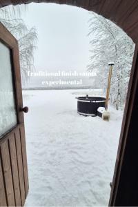 uma porta aberta para um quintal coberto de neve com uma placa em Raanu Apartments em Raanujärvi