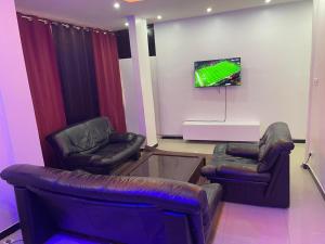 a living room with two chairs and a flat screen tv at Yoff Apixi 2 in Dakar