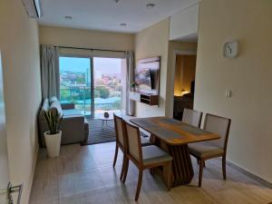 a dining room with a table and chairs and a living room at Edificio Ágora Villamorra Ensueño in Asunción
