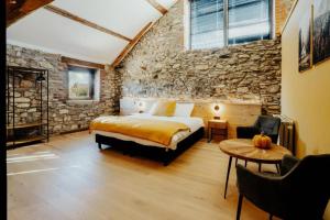 a bedroom with a bed and a stone wall at Les Landes de Bruyères in Waimes