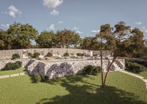 een tuin met een stenen muur en een boom bij Borgo Pascarosa in Ostuni
