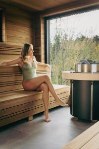 a woman is sitting in a sauna at Best Western Plus Le Roi Arthur Hôtel & Spa in Ploërmel